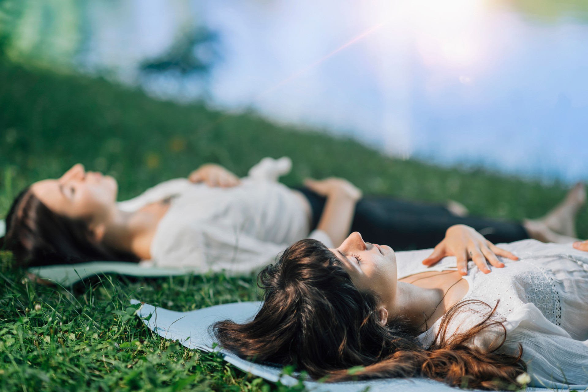 Meditation By The Water. Two Young Women Lying By The Water And Meditating